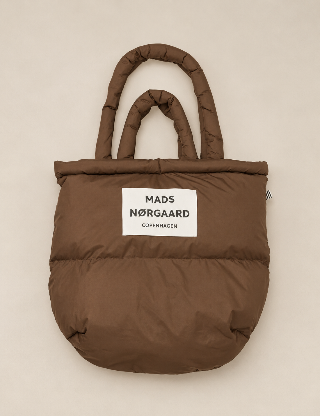 Light Ripstop Pillow Bag in cocoa brown, an oversized lightweight puffer tote bag with dual carrying handles and recycled polyester fabric.