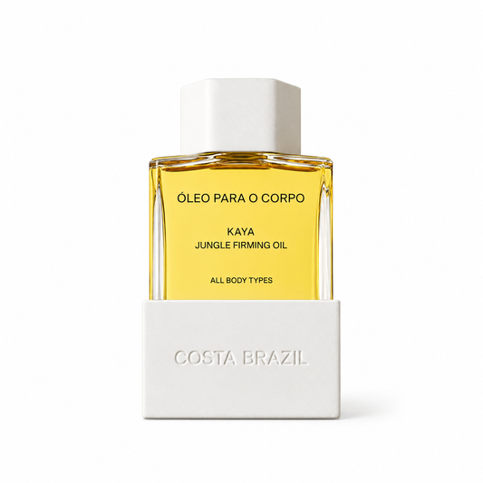 A bottle of Costa Brazil Kaya Jungle Firming Oil body oil, featuring a clear glass bottle filled with golden-yellow oil and a white cap, set against a white background with its white cardboard packaging base.