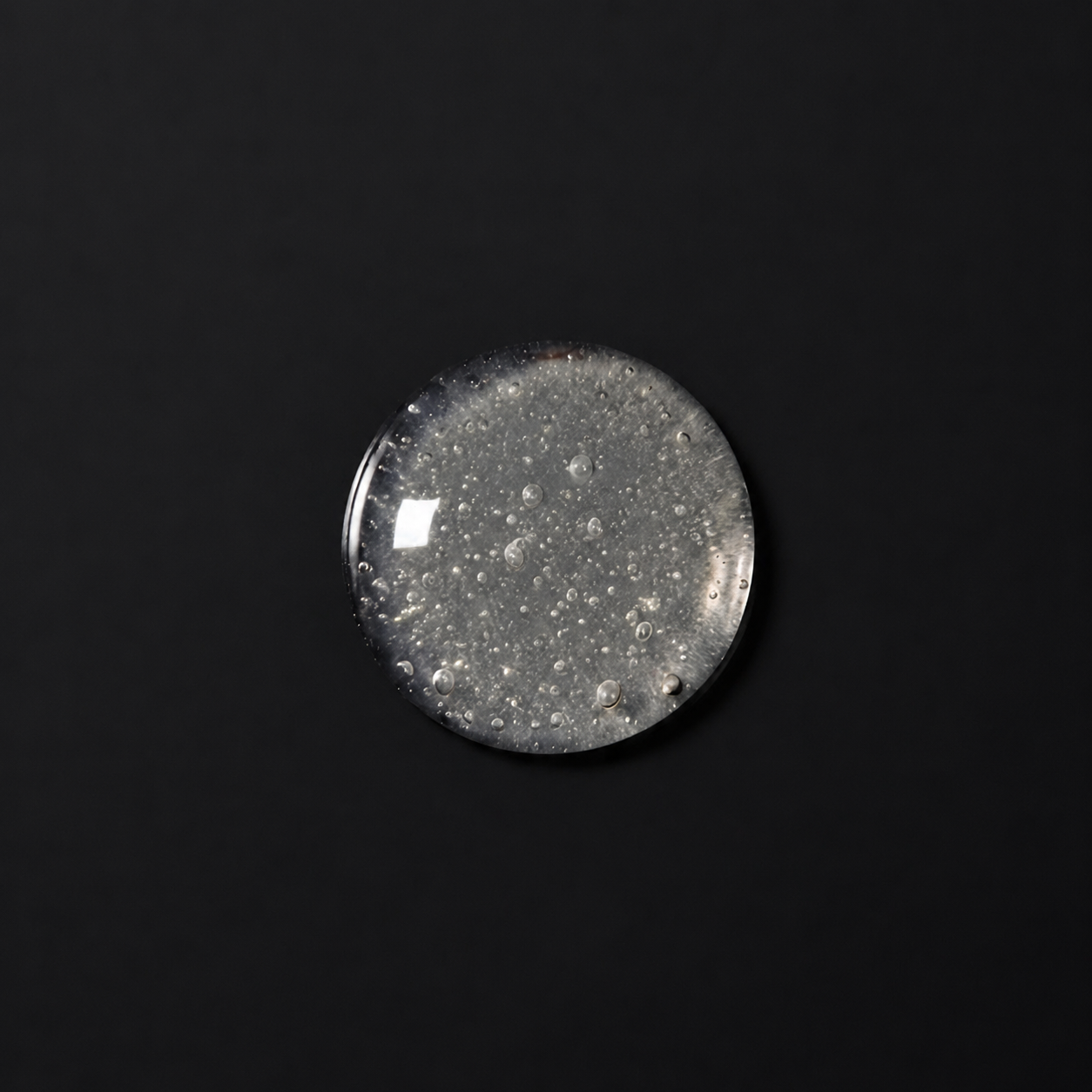 A round, clear cabochon gemstone with tiny white inclusions, photographed against a solid black background.