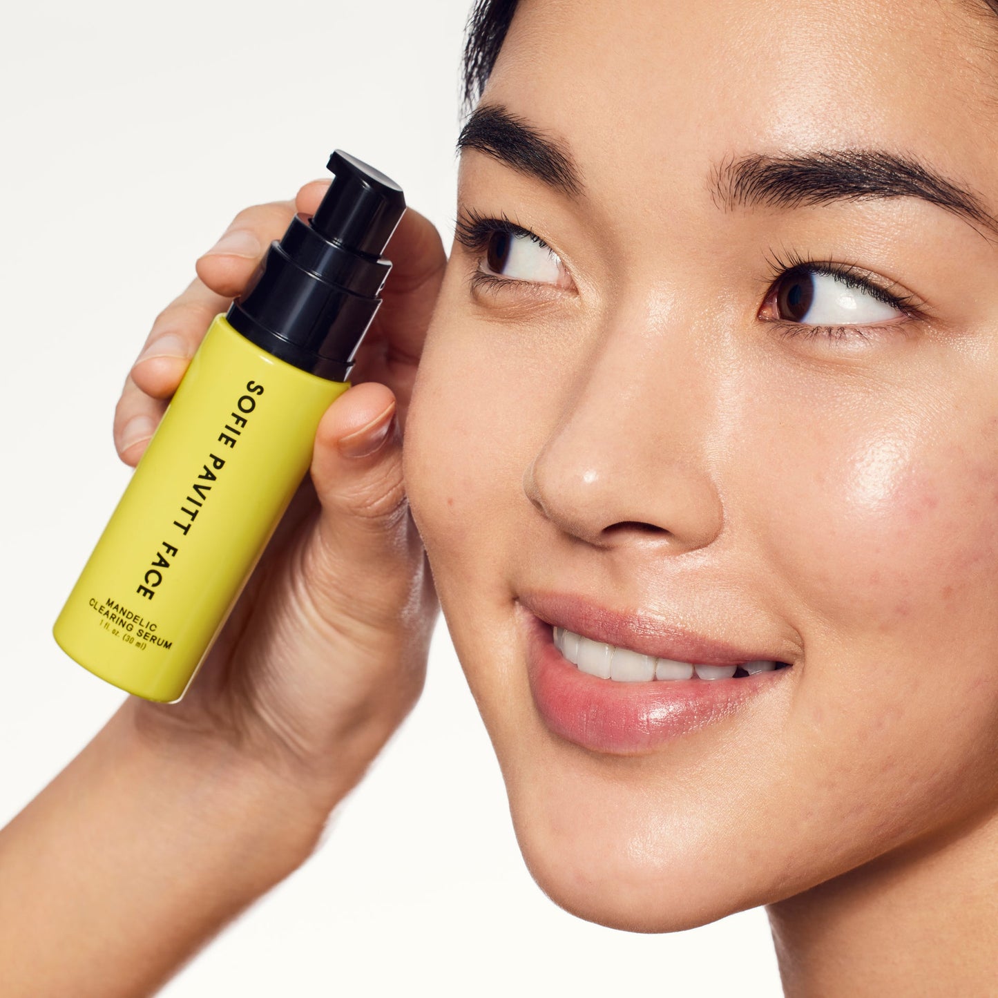 Person holding a yellow bottle labeled 'Super Puff Face' near their face on a white background
